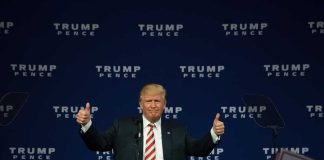 Person giving thumbs up at political event stage