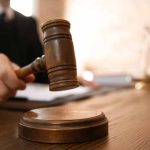 Judge with gavel on wooden desk courtroom setting