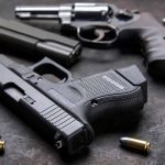 Three handguns with bullets on a metal surface