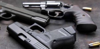 Three handguns with bullets on a metal surface