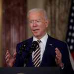 Man speaking at podium with microphones indoors