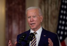 Man speaking at podium with microphones indoors