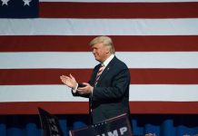 Man clapping in front of American flag background