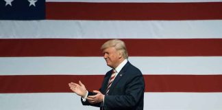 Man clapping in front of American flag background