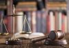 Gavel and scales on desk with books.