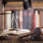 Gavel and scales on desk with books.