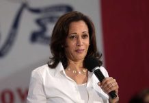 Woman holding a microphone and speaking on stage.