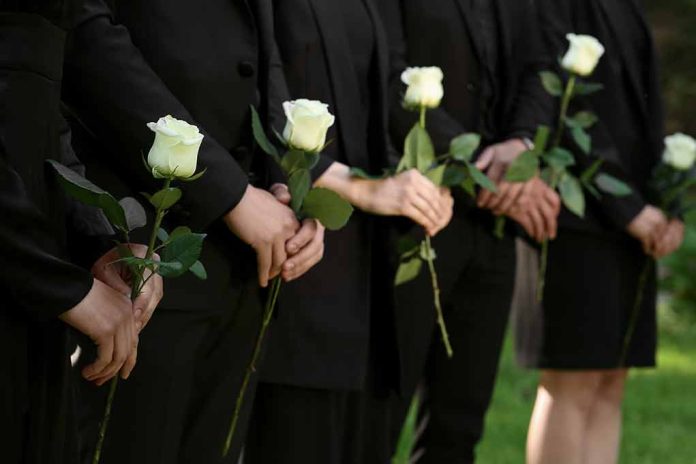 People in black holding white roses in a line.