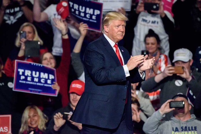 Man clapping on stage surrounded by supporters holding signs