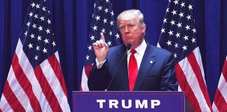 Person speaking at podium with American flags behind