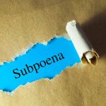 Subpoena text revealed through torn paper.