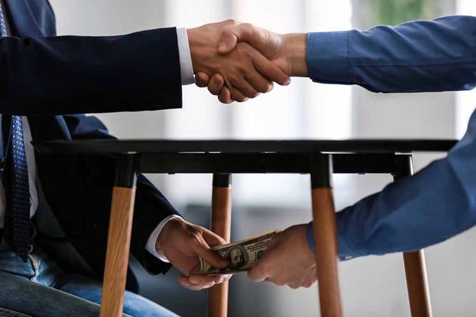 1225177960 featured image Handshake and exchange of money under the table.