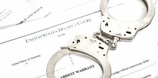 Handcuffs on top of arrest warrant document
