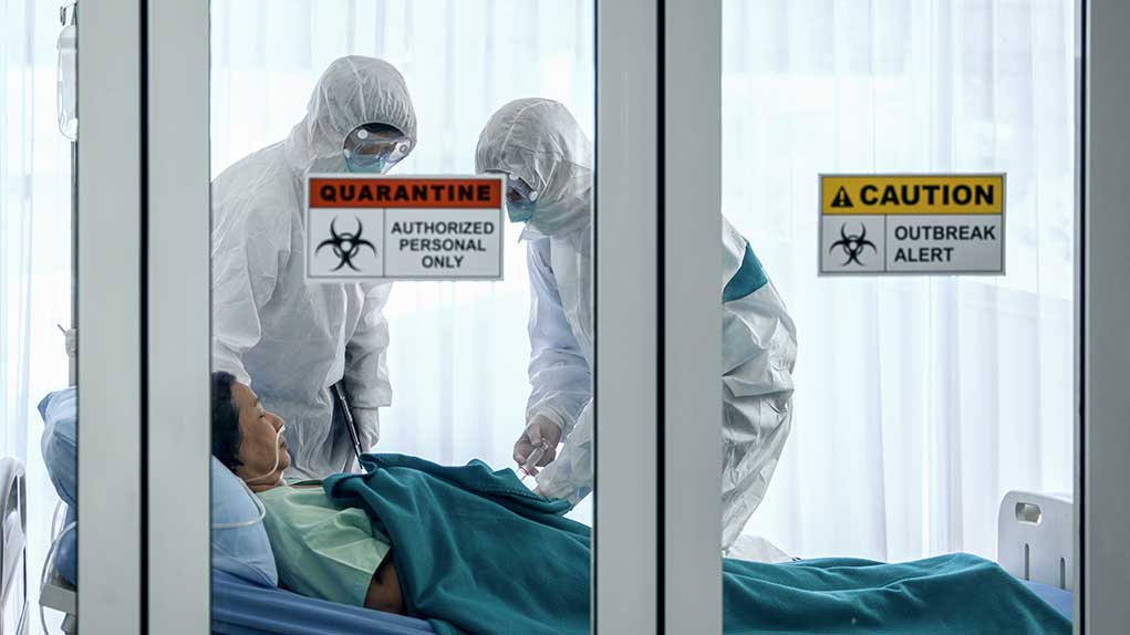 Healthcare workers in protective gear in quarantine room