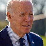 Elderly man in suit outside in daylight.