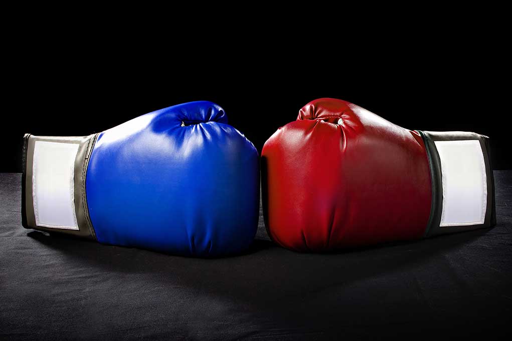 Blue and red boxing gloves facing each other.
