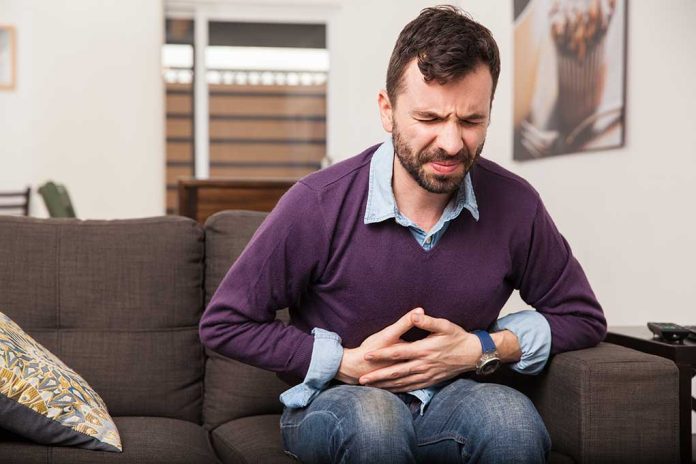 344063903 featured image Man sitting on couch, holding stomach in pain