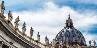 St Peter Basilica dome with statues and clouds