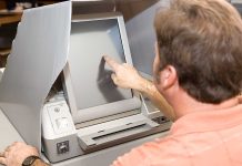Person using touchscreen voting machine in polling booth