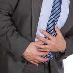 Man clutching stomach in pain wearing a suit