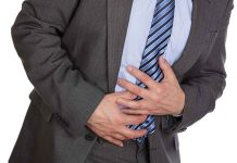 Man clutching stomach in pain wearing a suit
