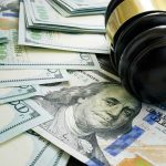 Gavel and hundred dollar bills on table