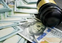 Gavel and hundred dollar bills on table