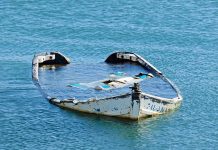 Half-submerged weathered abandoned boat floating on calm water