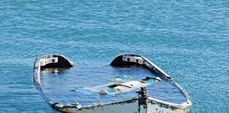 Half-submerged weathered abandoned boat floating on calm water