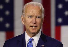 Man in suit speaking with American flag background