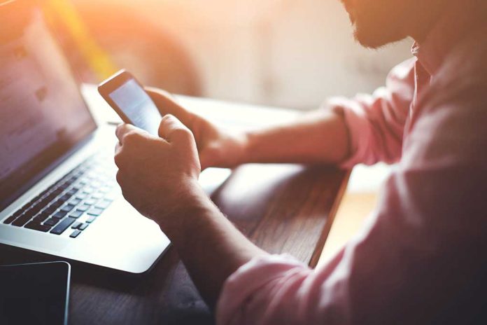 268450493 featured image Person using a smartphone and laptop at desk.