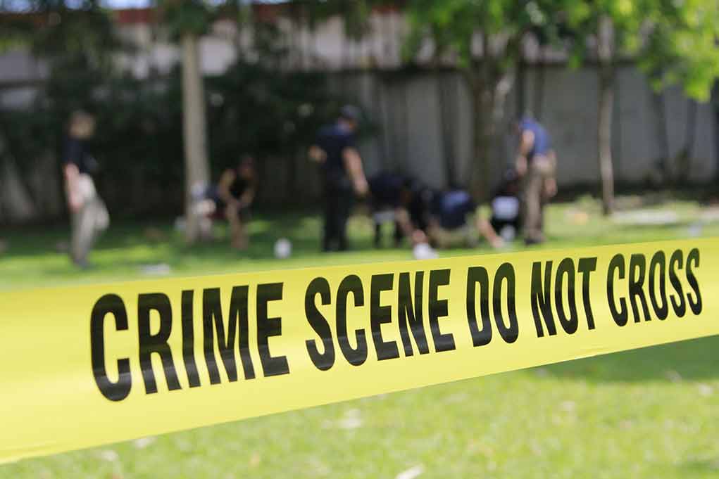 Yellow crime scene tape blocking grassy area