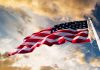 American flag waving against a cloudy sky