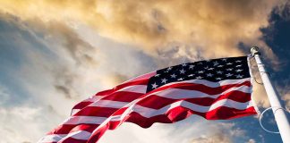 American flag waving against a cloudy sky