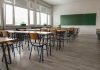 Empty classroom with desks chairs windows and chalkboard