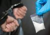 Handcuffed person with small bag of white powder
