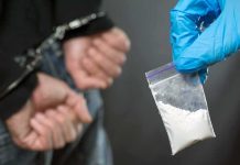 Handcuffed person with small bag of white powder