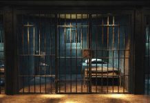 Empty prison cell with metal bars and bed