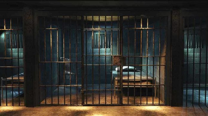 1427252378 Empty prison cell with metal bars and bed