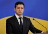 Man in suit speaking at podium with microphones
