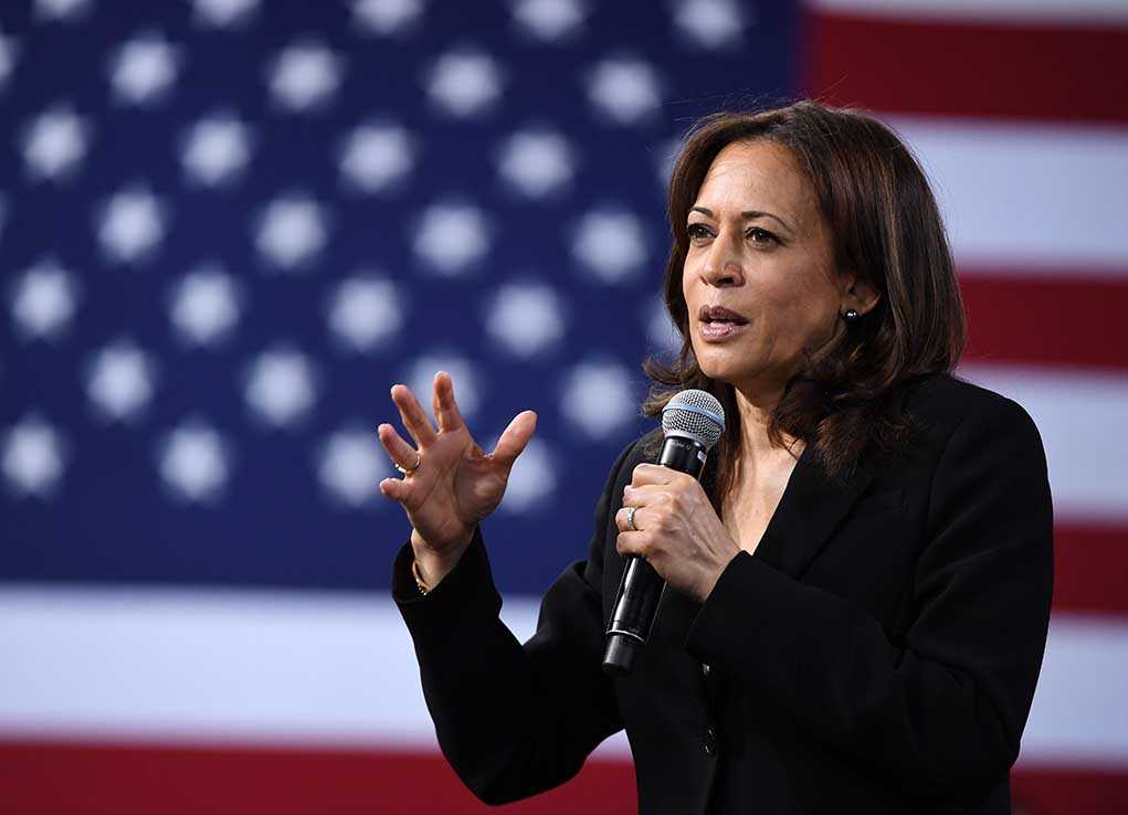 Woman speaking into microphone with American flag backdrop