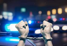 Hands in handcuffs in front of police cars