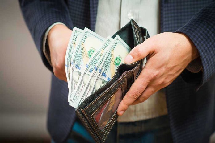 253526959 Person holding wallet full of hundred dollar bills