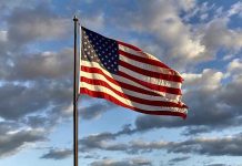 American flag waving against cloudy sky