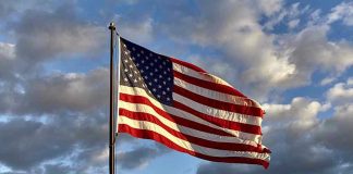 American flag waving against cloudy sky