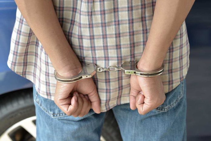 A person in handcuffs viewed from behind, wearing a plaid shirt and denim jeans