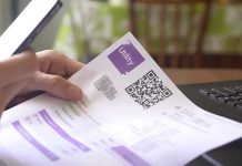 Hand holding utility bill with QR code
