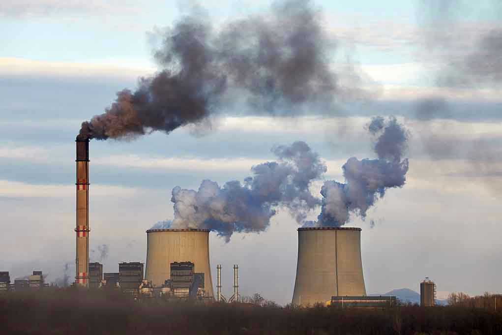 Industrial plant emitting black smoke into the sky
