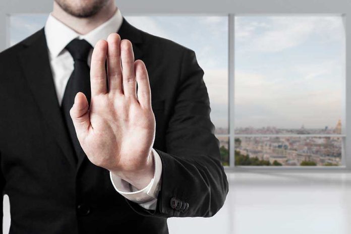 275001506 Person in suit with hand raised in stop gesture.