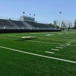 Empty football field with bleachers in background